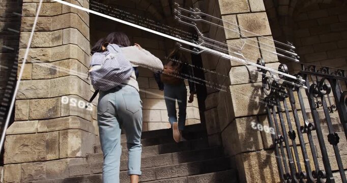 Two friends climbing steps with backpacks, approaching arch causing timeline overlays for tour