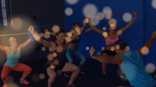 Vertical video: Cueing coach guiding 5 in tanks or bras doing overhead band squats for form gym boke