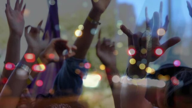Festival crowd raising hands to music beat, celebrating while bokeh lights syncing with wristbands