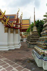 Fototapeta premium Wat Pho temple complex in Bangkok with tourists admiring ornate stupas