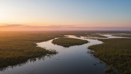 Obraz premium Flowing winding river snaking through wetland at sunrise, with vegetated island and side channels