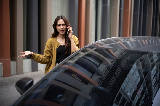 Woman feeling stressed having trouble with her car while making a phone call outdoors