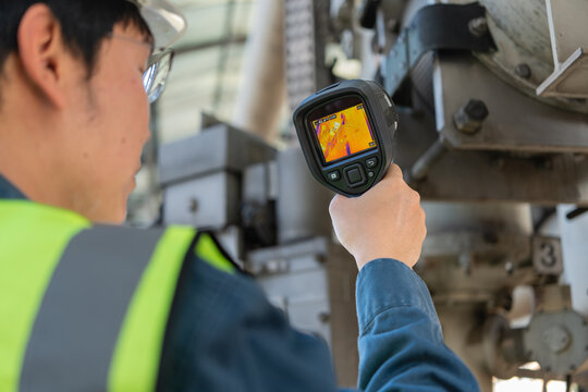 Engineer using an infrared thermal camera to inspect industrial equipment in energy infrastructure, supporting predictive maintenance, safety checks, and reliable power system operation.