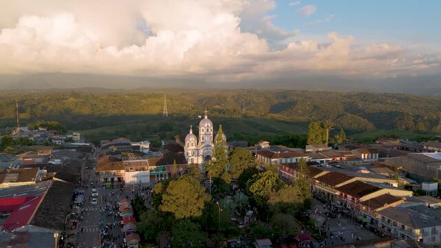 A stunning aerial shot of Filandia, Quindio, showcasing vibrant buildings and a church under dramatic clouds.