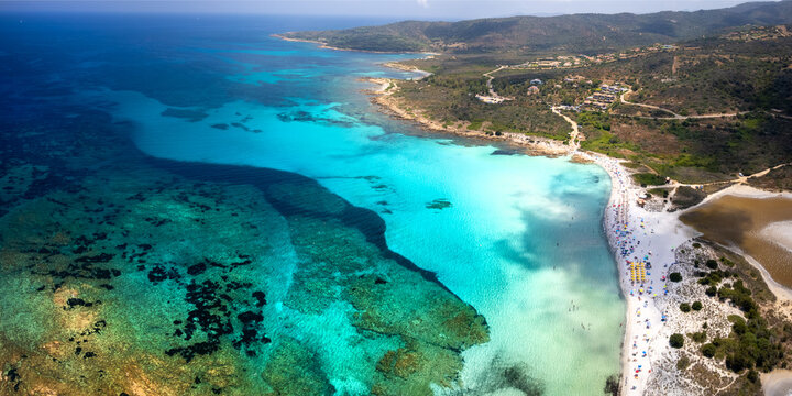 Sardinia Isuledda beach aerial drone view of cloud shadows on turquoise water. European Caribbean aerial view with salt lagoon and yellow rocks. Mediterranean tropical paradise in Sardegna island