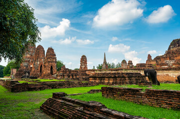 Fototapeta premium Ancient stupa towers in Ayutthaya historical park, Thailand. Ruins of former Siam capital under blue sky on sunny day. Famous travel destination with cultural heritage and Buddhist history.