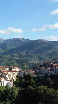 Charming hilltop village with traditional houses nestled among green mountains under a clear blue sky in Aieta, Italy. Picturesque landscape with natural beauty and historic architecture.