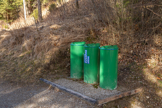 Three green recycling bins labeled Tiroler Zugspitz Arena on a mountain hiking trail