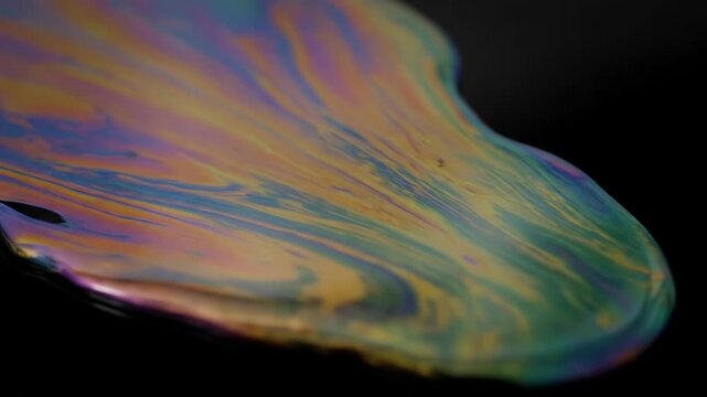 Iridescent liquid spreads slowly, revealing a spectrum of vibrant colors. This abstract, mesmerizing display creates a beautiful, fluid pattern.