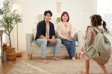 Obraz premium Parent Helps Child Prepare for School While Another Parent Shares a Moment in the Living Room