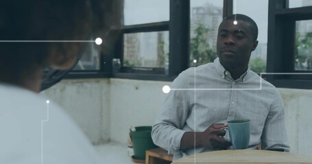 Holding man in gray shirt cradling green ceramic mug at round wooden table in sunroom, overlay
