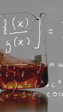 Vertical video: Amber liquid in beaker reacting to ice cube entering forming waves lab math overlay