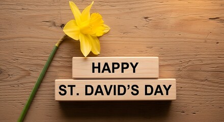 Naklejka premium Wooden blocks with happy st. davids day message and yellow daffodil on wooden surface