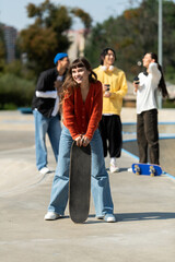 Fototapeta premium Young friends enjoy a sunny day at the skate park while capturing fun moments together
