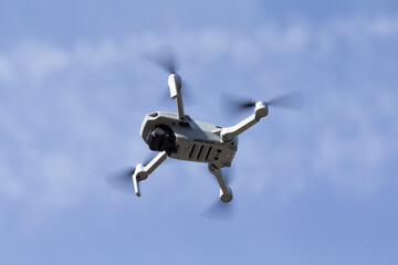 Drone Flying Overhead Against Blue Sky with Clouds
