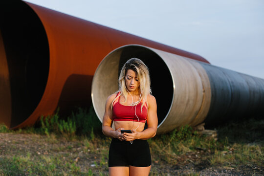 Full length portrait of a female athlete taking a break to play music on her smartphone. 
