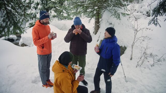 Group of hikers enjoying lunch break in snowy forest