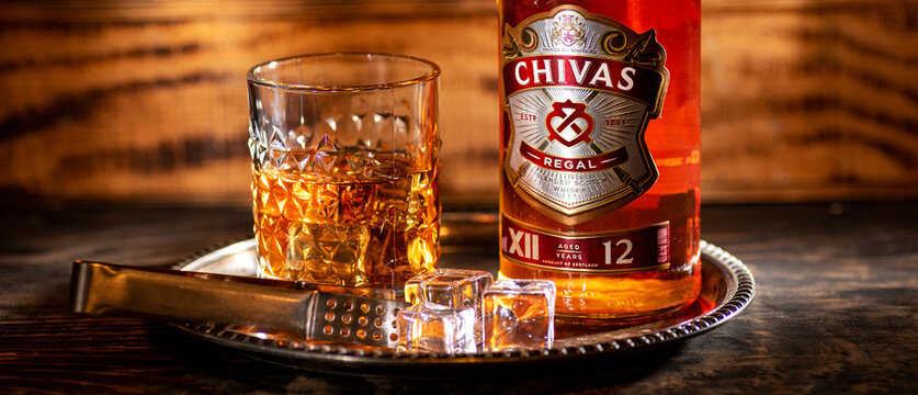 Chivas Regal 12 whisky glass with ice cubes and bottle on bar tray