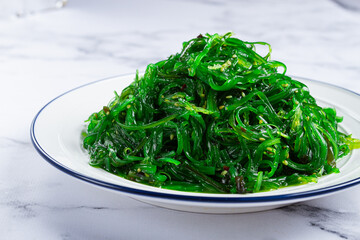 Chuka salad made from fresh seaweed, with sesame dressing, served on a white plate, no people, © Gala_Didebashvili