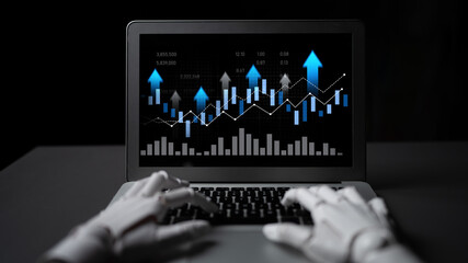 Robotic hands engaged on a laptop, showcasing a stock market chart on the screen. The display...