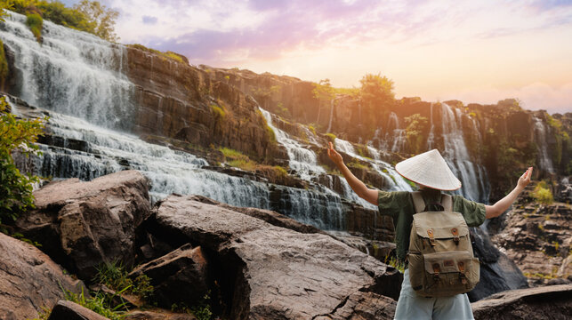 Traveler raising arms facing Pongour waterfall cascade with terraces Da Lat city, Vietnam