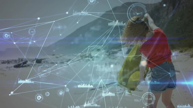 Woman lifting yellow cloth and walking on beach, making cloth billow while tech HUD intensifying