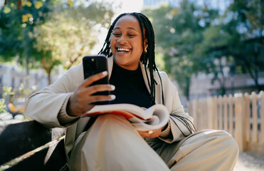 Smiling woman creating digital content on tablet in city park digital nomad lifestyle authentic...