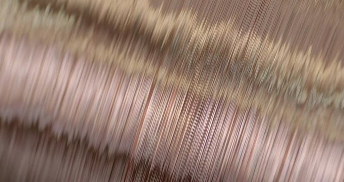 A cable-making machine is in operation. A spool of copper wire is rotating. Close-up handheld shot, real time speed.