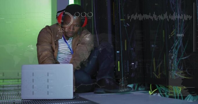 Typing technician in red muffs monitoring server rack and laptop in data center as overlays appear