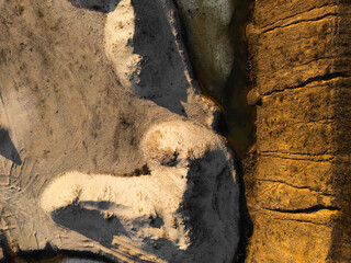 Obraz premium Aerial view of quarry edge with sand, rock and water textures