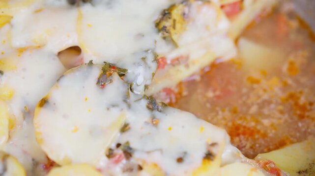 Closeup baked meat gratin with potatoes, tomato slices, gooey melted cheese, golden breadcrumb crust, herb flecks, warm rustic lighting, home cook plating comfort meal