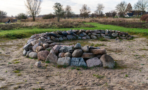 Fire pit ring constructed from large natural granite and fieldstone boulders placed on sandy ground in an open grassy park area. Outdoor campsite feature designed for campfire gatherings and recreatio