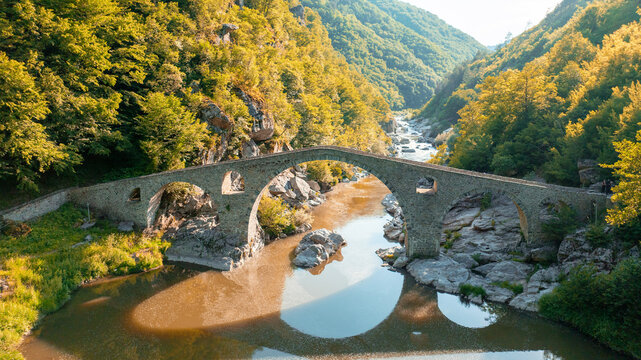Devils Bridge aerial view Rhodope mountains Bulgaria summer landscape. Ancient stone architecture Arda river water landmark. Drone shot historic bridge Balkan mountains travel photography scenery view