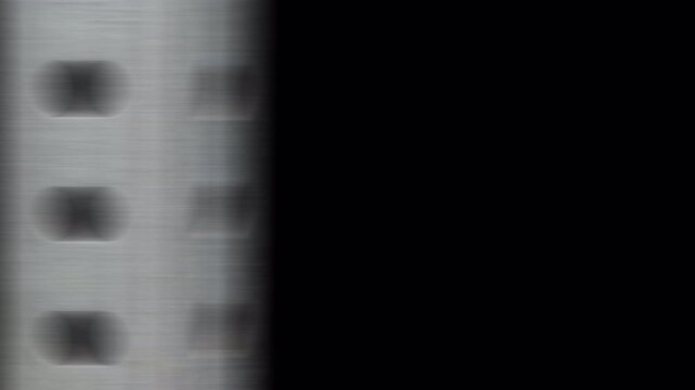 Abstract close-up of a white vertical object with dark square patterns on a black background.