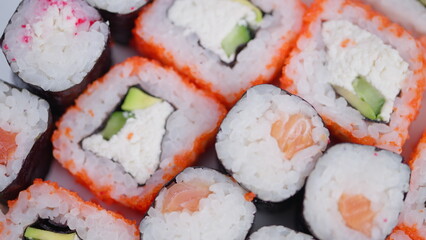 Bright sushi presentation. Colorful seafood and rice slices. Appealing salmon and avocado sushi closeup shot. Vivid arrangement of fish and rice rolls on display © beholdereye