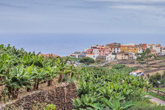 Vista pintoresca del pueblo de Agulo, con sus casas de colores rodeadas de densos cultivos de plataneras sobre un acantilado que asoma a las aguas del oc&eacute;ano Atl&aacute;ntico en La Gomera.