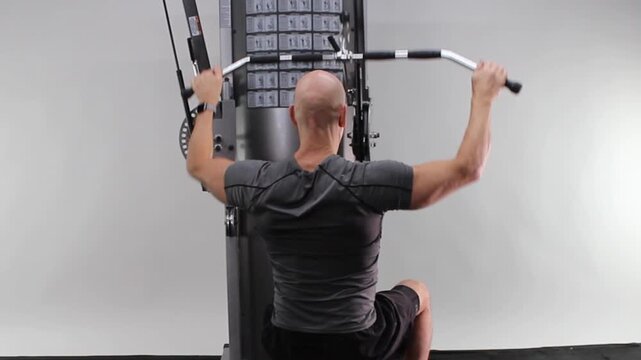 Middle-aged man performing lat pulldown, rear view