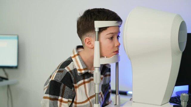 Young boy having eye examination with auto refractometer