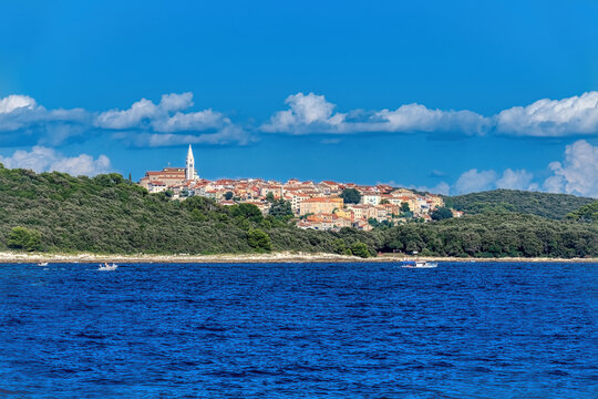 scenic coastal view of vrsar old town in istria croatia with the iconic church tower and white clouds over blue adriatic sea during daytime