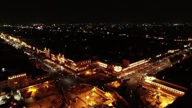 Aerial drone showing Indian city Jaipur at night with traffic passing by decorated buildings and horizon showing city