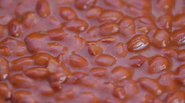 Vivid bean closeup, Closeup of simmering red beans with rich textures and warmth, Detailed view of glossy red beans in warm sauce emphasizing texture and culinary appeal
