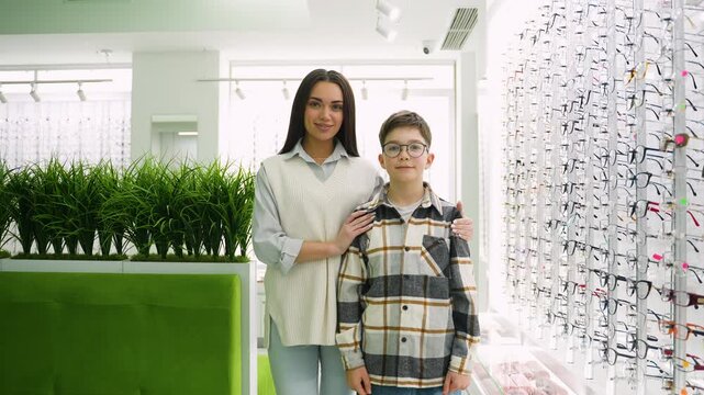 Mother and son showing thumbs up in optical store