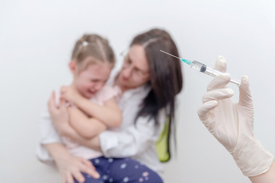 Crying child comforted by mother while medical worker holds syringe for vaccination, concept of pediatric immunization, childhood vaccines and healthcare prevention