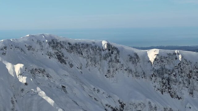 Snow covered mountain ridge and alpine peaks near Krasnaya Polyana at altitude 2200 meters with distant horizon and winter landscape panorama. Mountain tourism promotion, winter travel