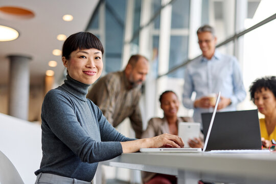 Portrait of a group of young business people having a meeting in the office. Teamwork and success concept, portrait of a smart young businesswoman using a laptop