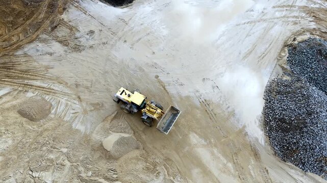 A loader tractor on a sand quarry levels the surface of the sand. High quality 4k footage