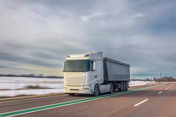 Obraz premium Modern white freight truck transporting cargo on winter highway. Logistics truck on road.