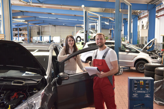 mechanic and customer talking in a workshop to repair a vehicle