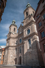 Iconic Dom zu St. Jakob roman catholic cathedral rises in Innsbruck historic center with baroque towers, green domes and alpine vista, cinematic pilgrimage landmark ideal for faith campaigns.