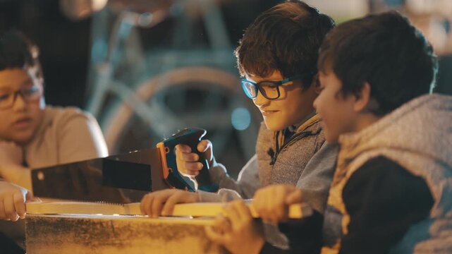 Young boys learning woodworking skills sawing a wood plank